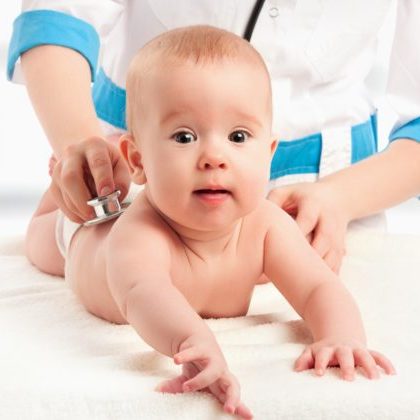 baby at the doctor pediatrician. doctor listens to the heart with a stethoscope